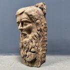 Verweerd gesneden houten hoofd van man met baard