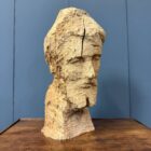 Grof uit houten stam gesneden hoofd van een man